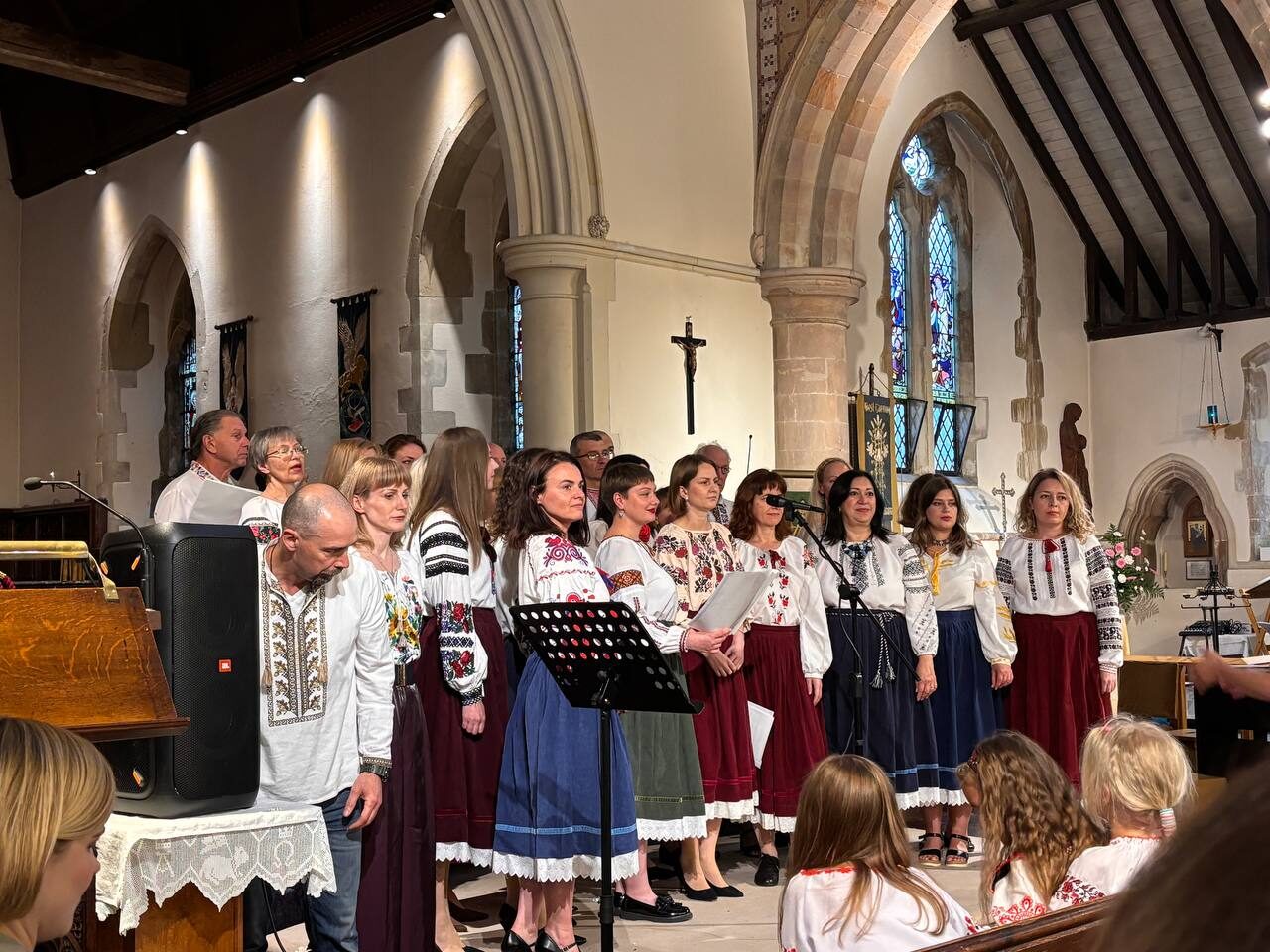 The choir performing beneath dramatic lighting inside a historic church