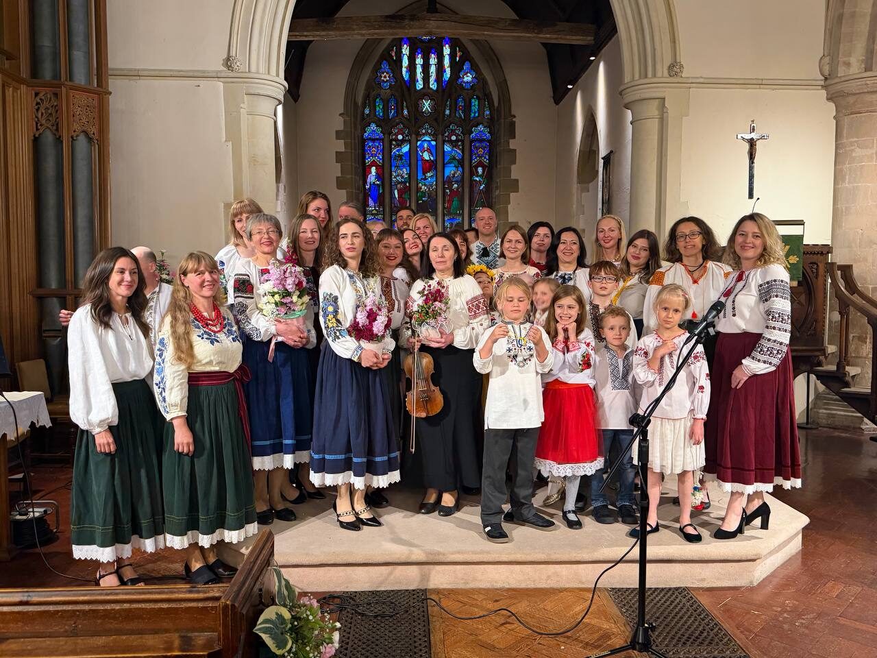 Ukrainian Voices choir presented with flowers after a concert, with violin in hand.
